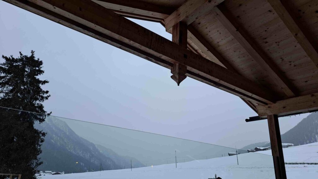 Blick aus einem Holzhaus in heimeliger Winterlandschaft in den Bergen